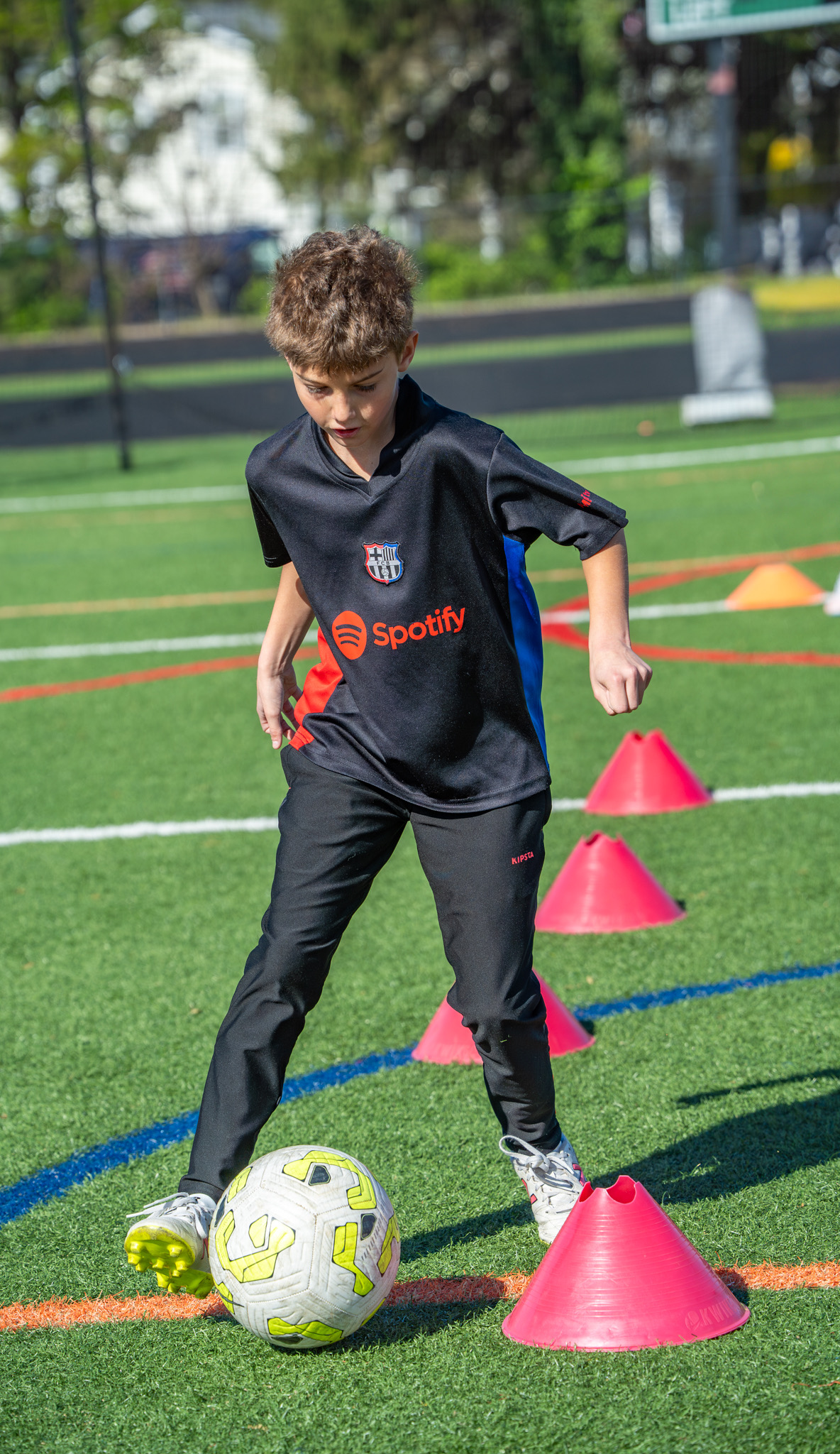 Young player focused on ball control through red cones
