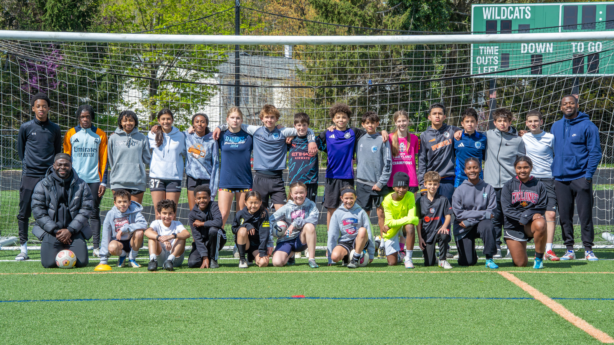 Full squad team photo in front of goal net on turf field