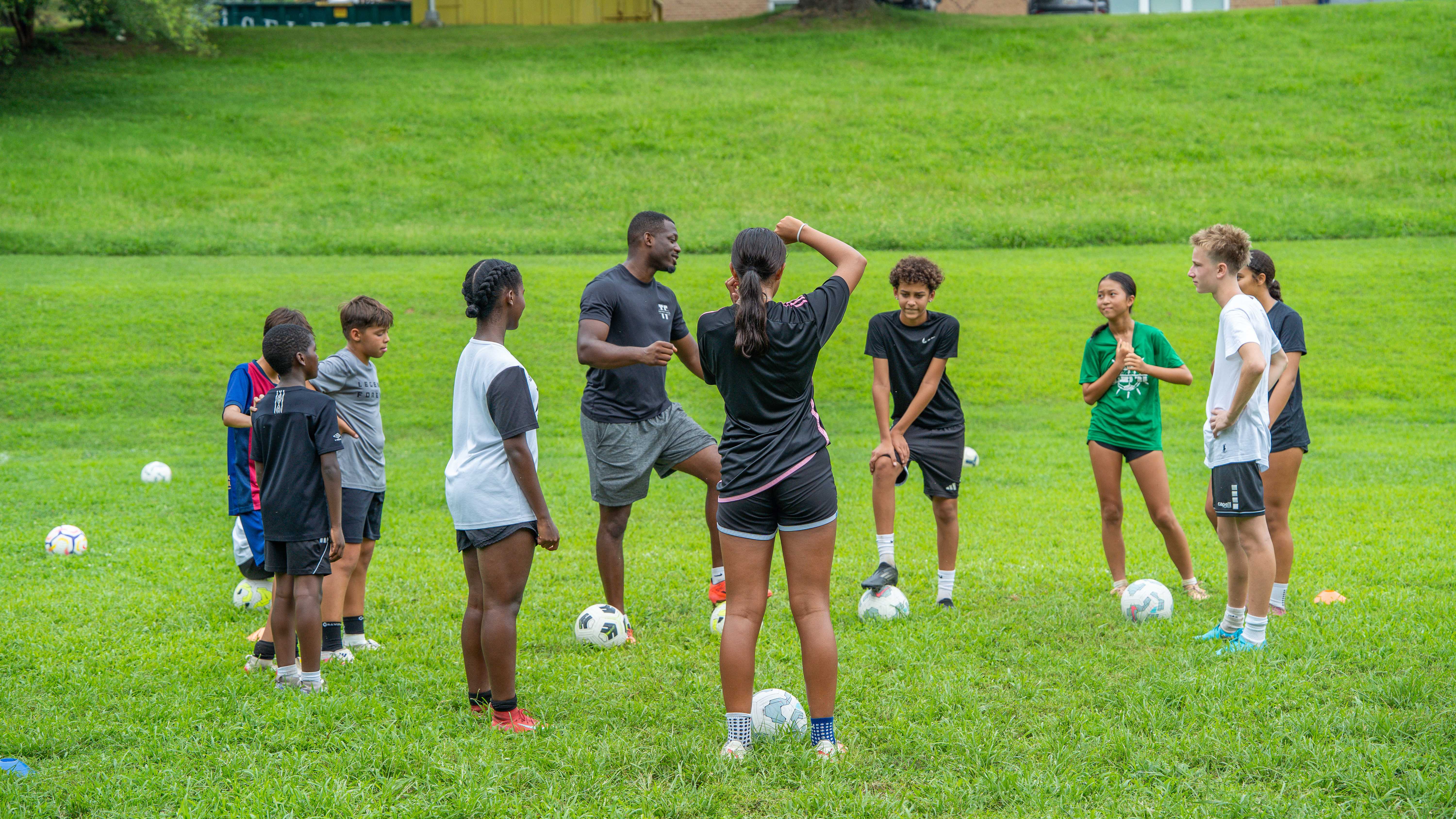 Coach leading warm-up circle with players on grass field