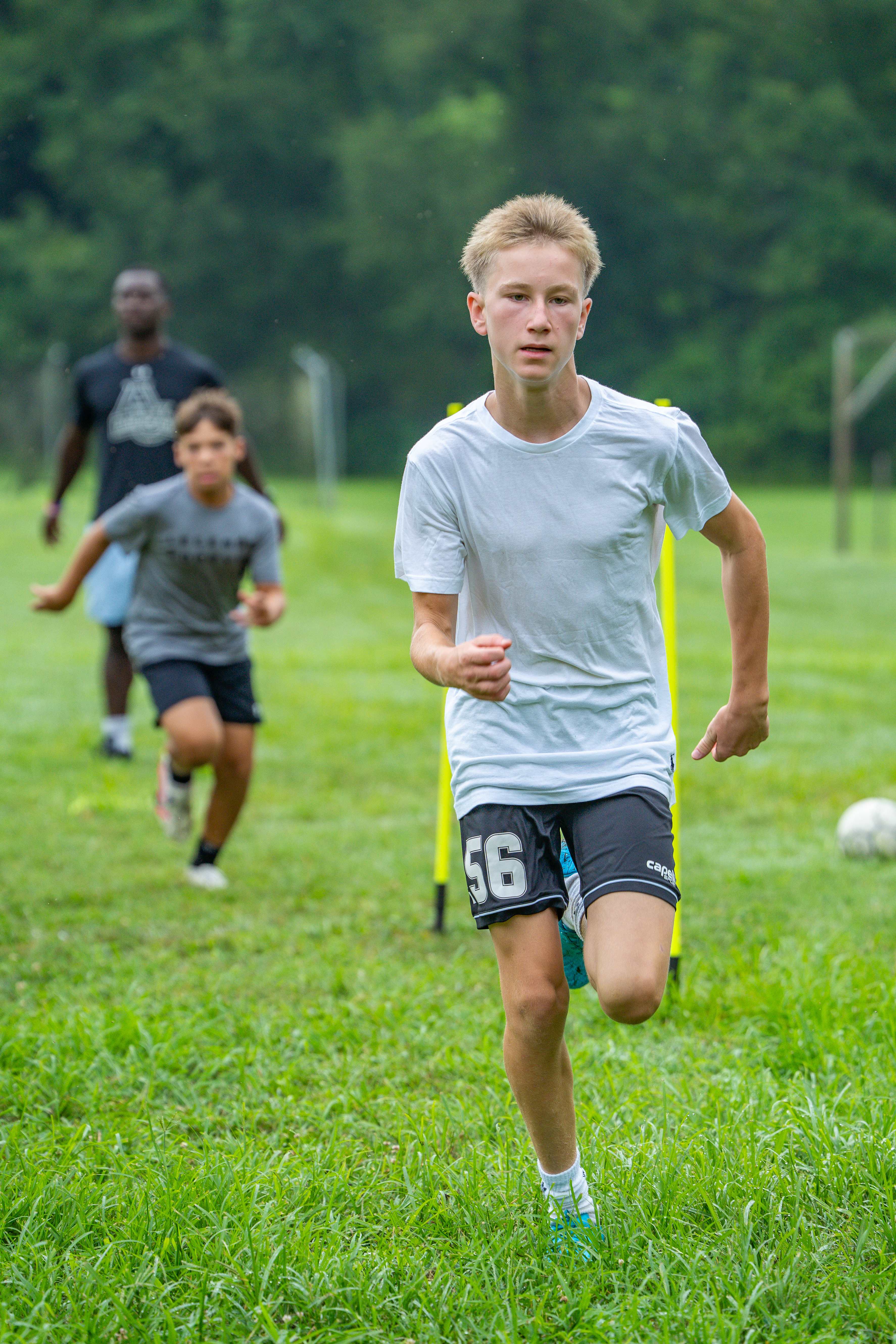 Player sprinting hard through conditioning drill with coach